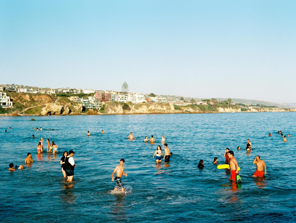 People enjoying a summer day swimming at Newport Beach, California with scenic views.