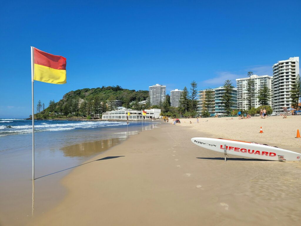 A vibrant beach scene at Gold Coast, Australia, with lifeguard gear and clear skies.