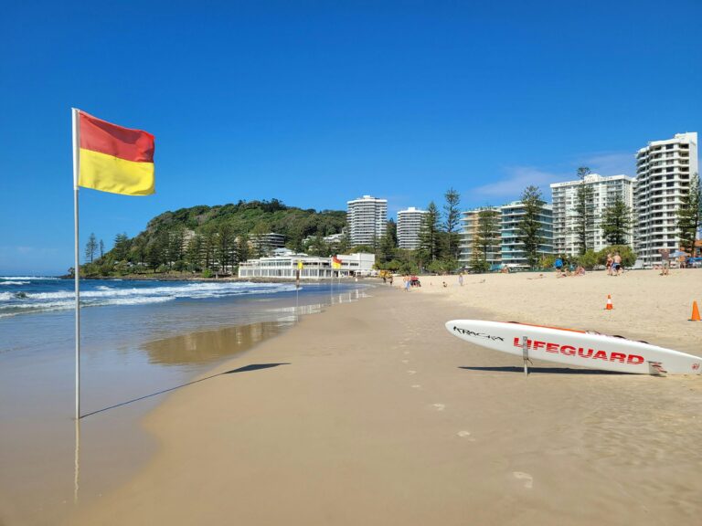 A vibrant beach scene at Gold Coast, Australia, with lifeguard gear and clear skies.