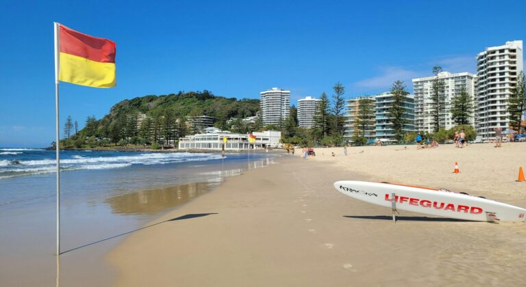 A vibrant beach scene at Gold Coast, Australia, with lifeguard gear and clear skies.