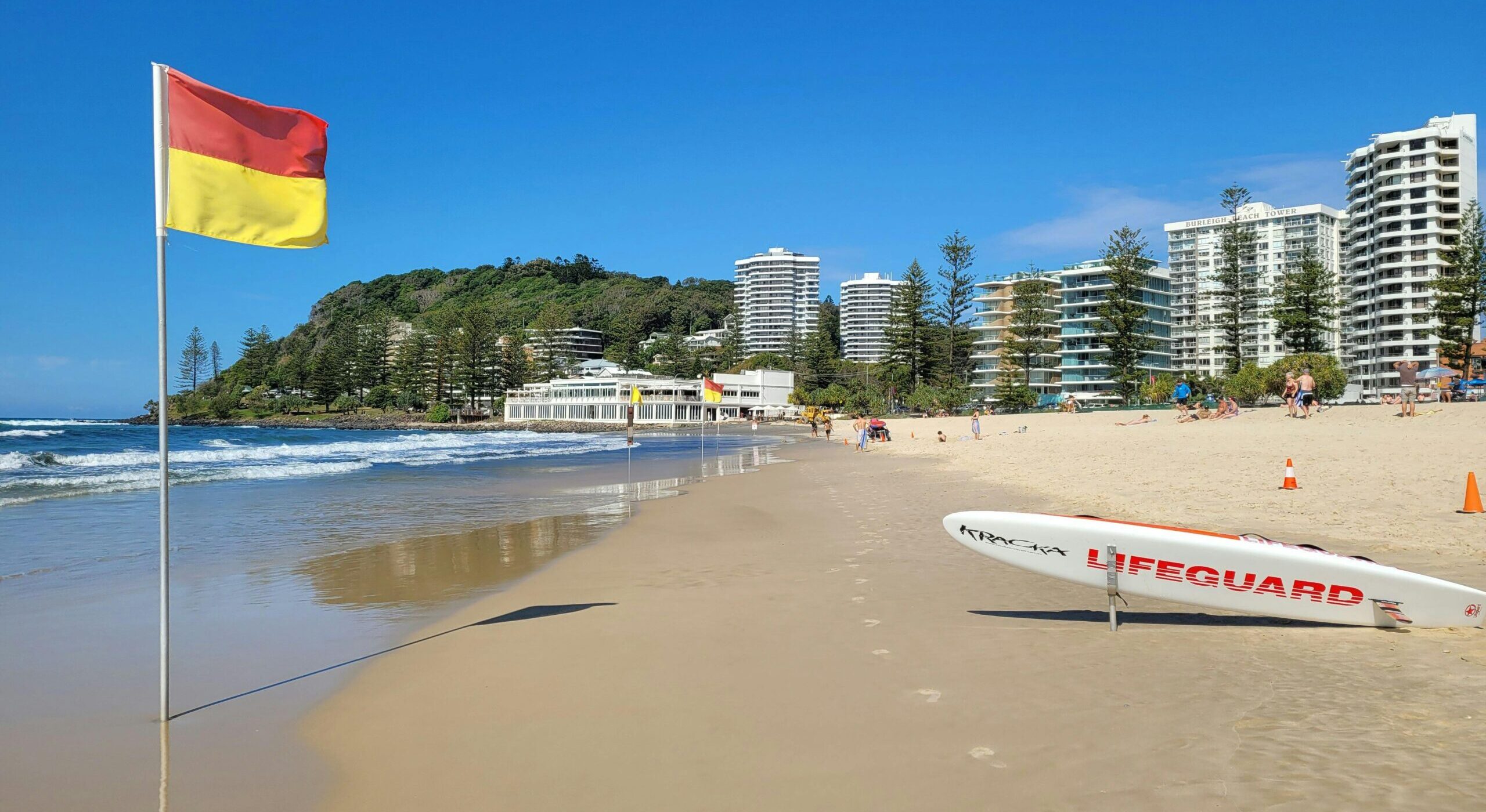 A vibrant beach scene at Gold Coast, Australia, with lifeguard gear and clear skies.