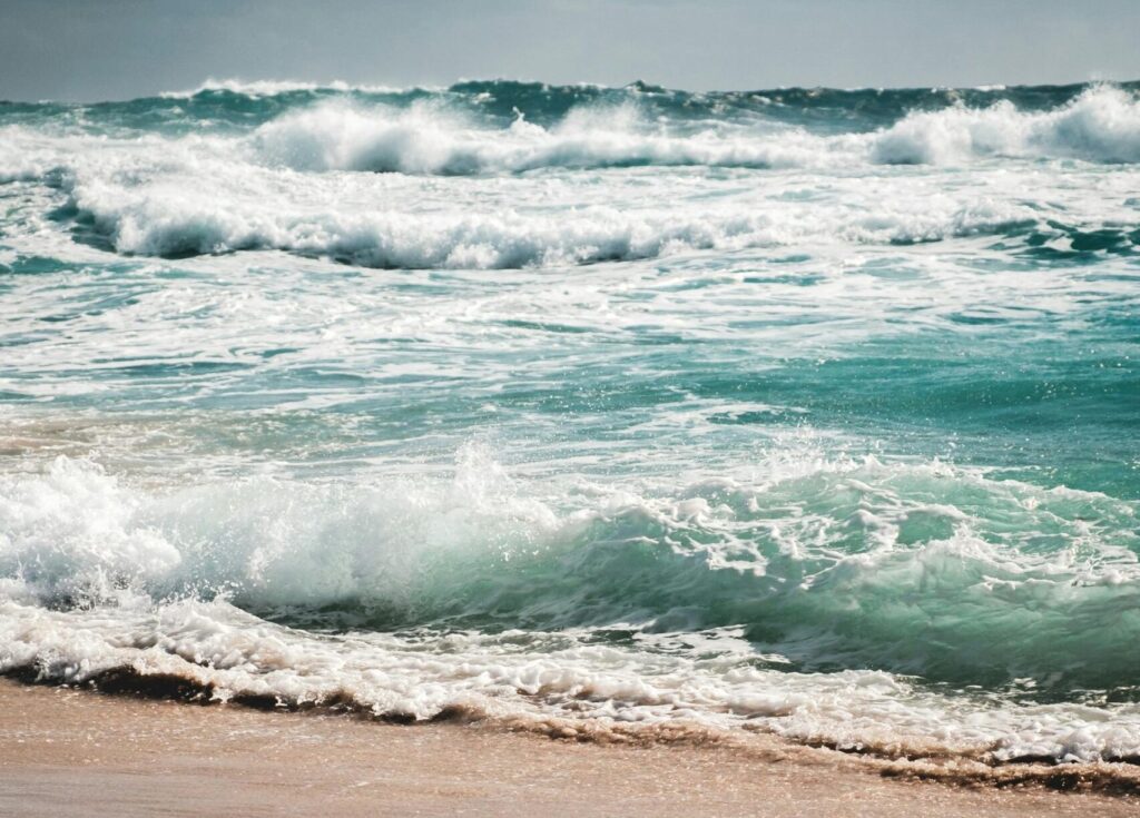Amazing view of stormy azure sea with foamy waves rolling on wet sandy beach on cloudy overcast day